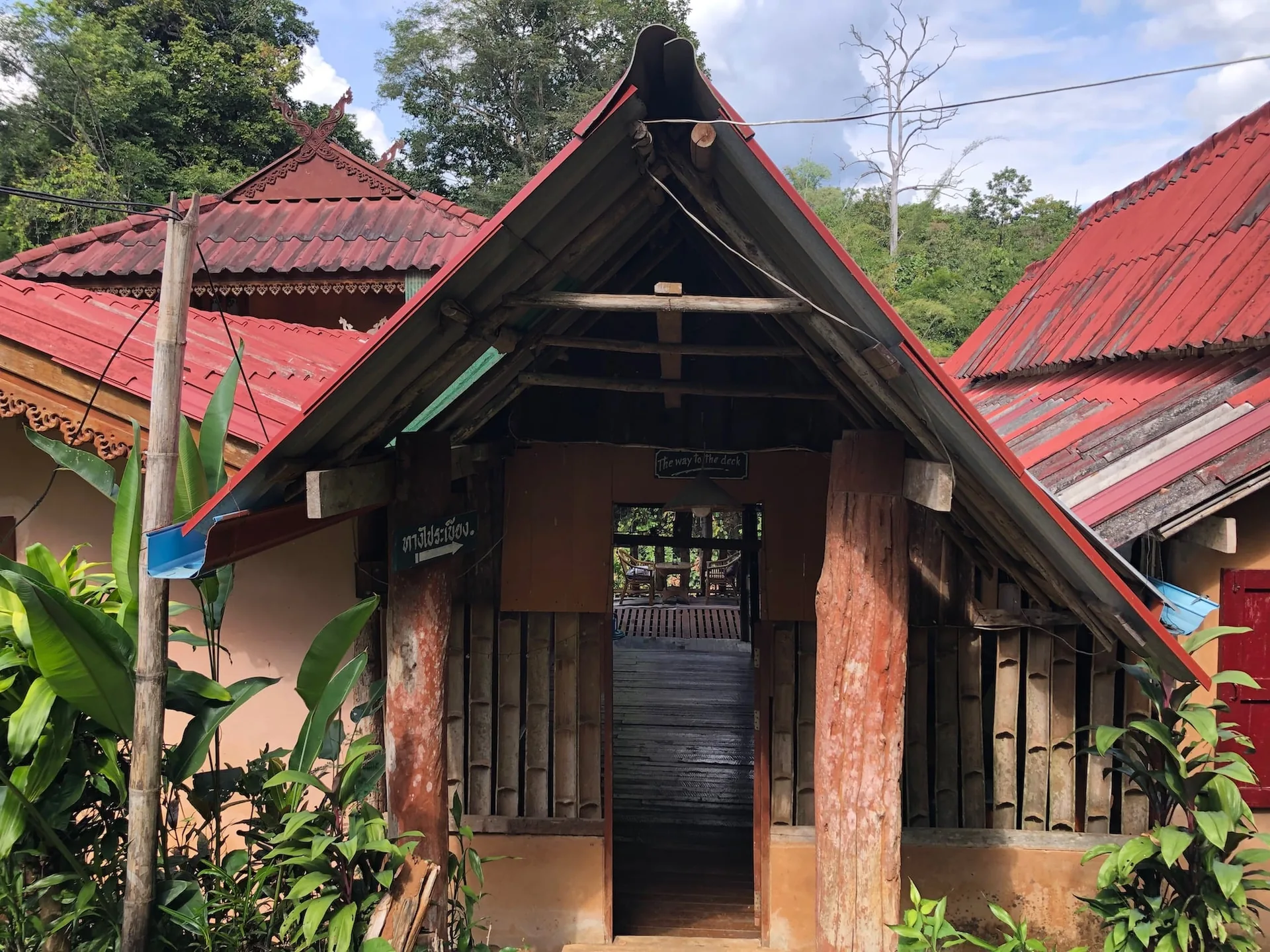 Red-roofed brick and timber lodge building among tropical plants