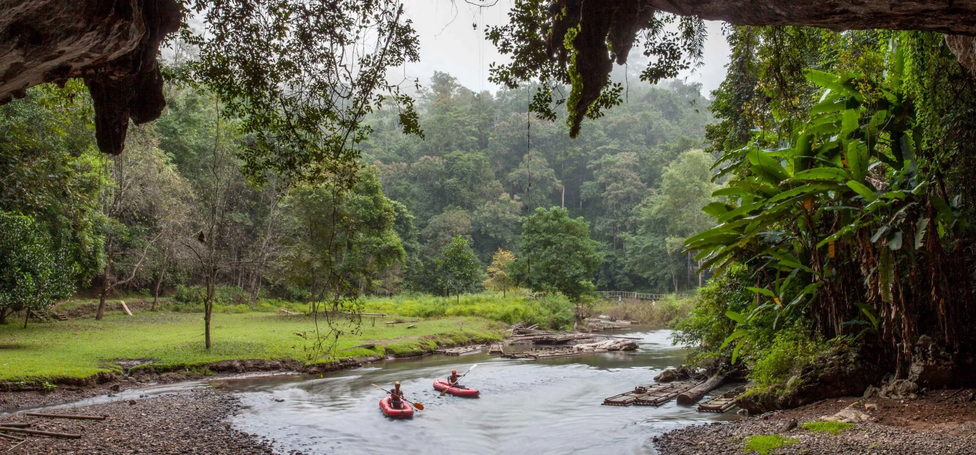 Kayakers paddling along the river toward Tham Lod