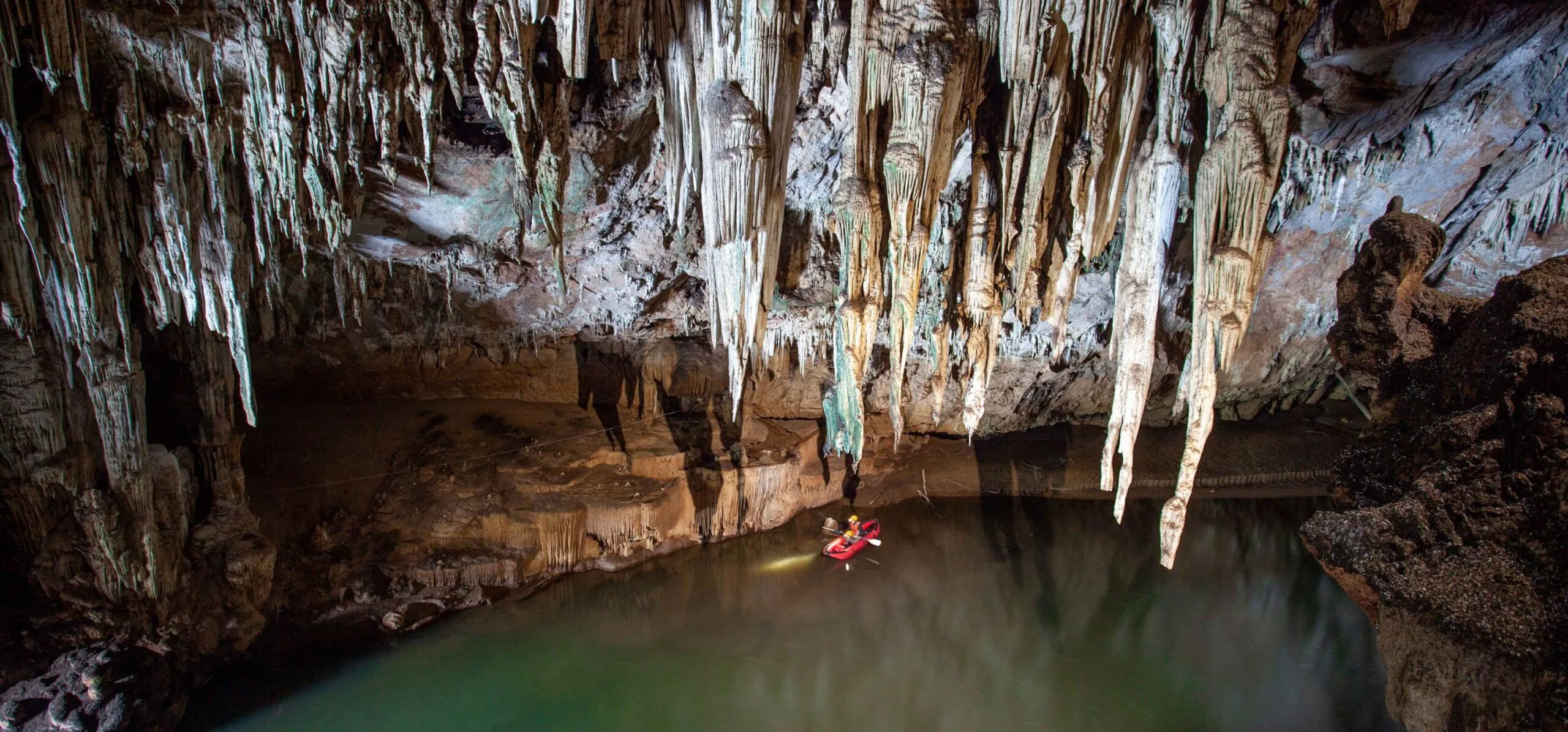 Stalactites above the turquoise underground river in Tham Lod