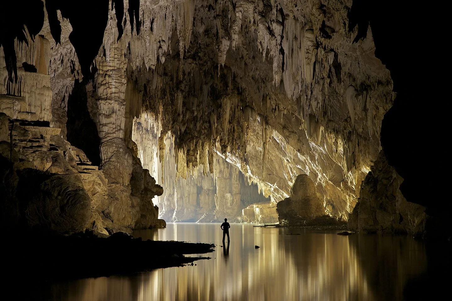 Figure reflected in the still water of Tham Nam Lod cave