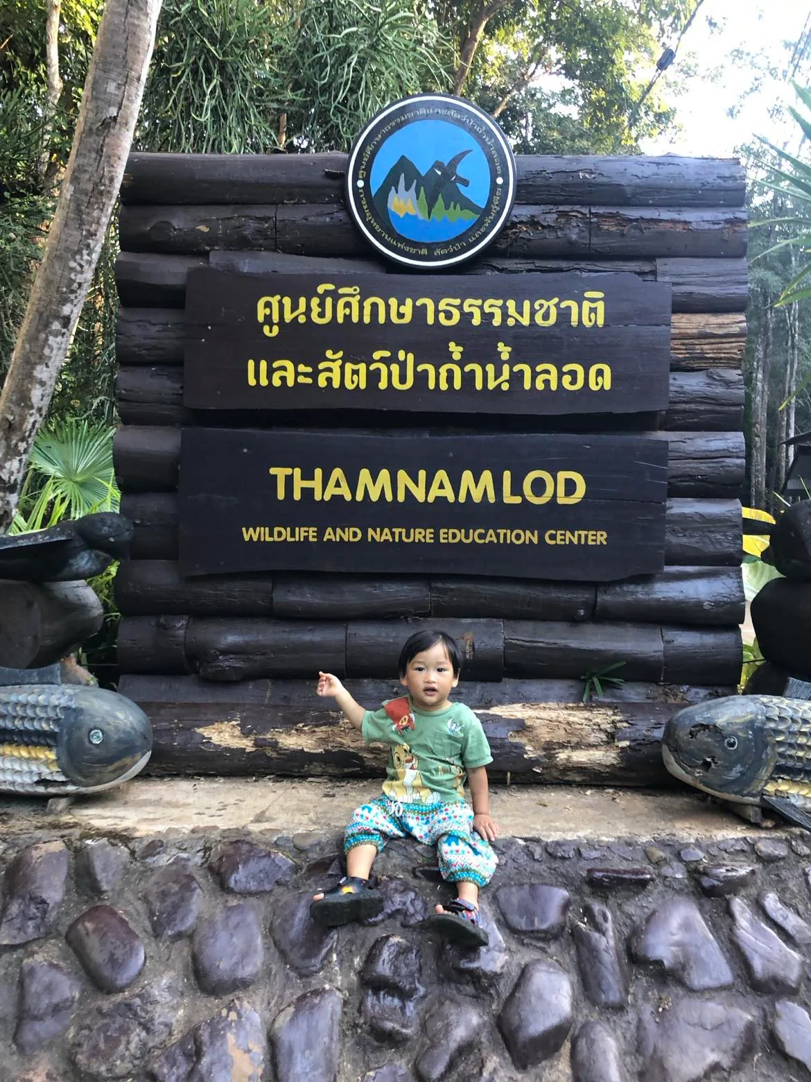 Child sitting in front of the Thamnamlod Wildlife and Nature Education Center sign